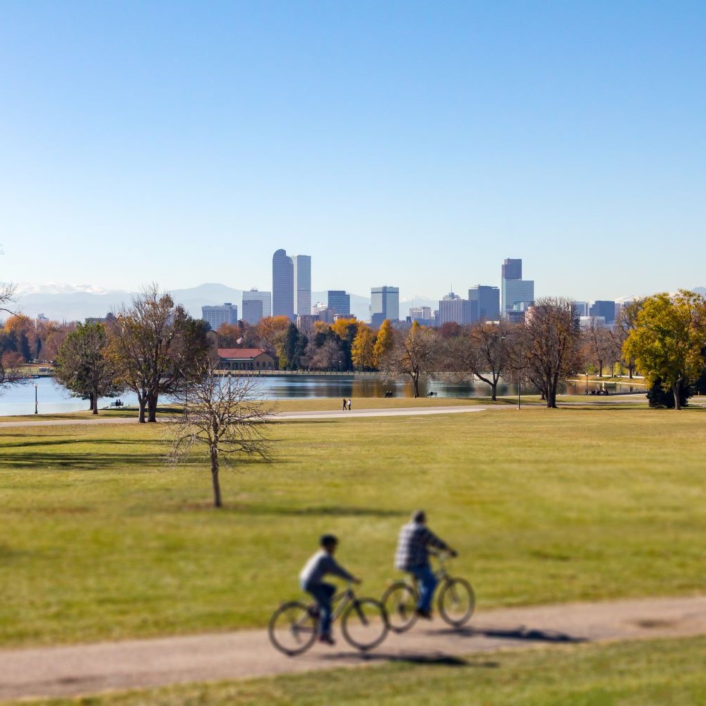 two bikers on trail with downtown Denver in backdrop