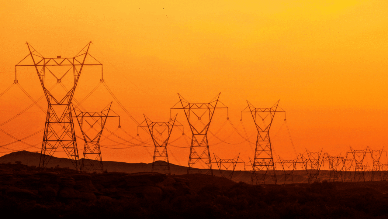Power lines in front of a mountain in the sunset