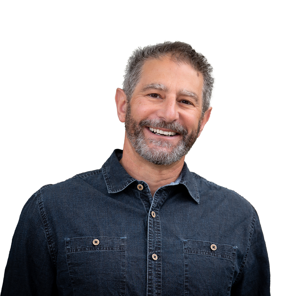 Jon-Goldin-Dubois Smiling man with short gray hair and beard wearing a blue button-up shirt against a plain background.