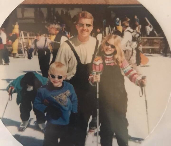 468007554_10161847051417937_6937080084889336595_n Three people wearing ski gear and sunglasses stand on snow with ski poles, smiling at the camera. Other skiers and a building are visible in the background.