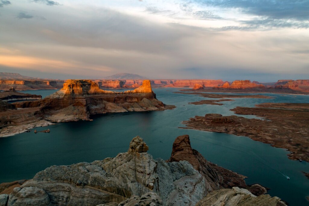 Lake Powell Nevada Small A wide view of Lake Powell with rock formations and mesas in the water, under a partly cloudy sky at sunset—a striking scene reflecting nature’s climate resilience.