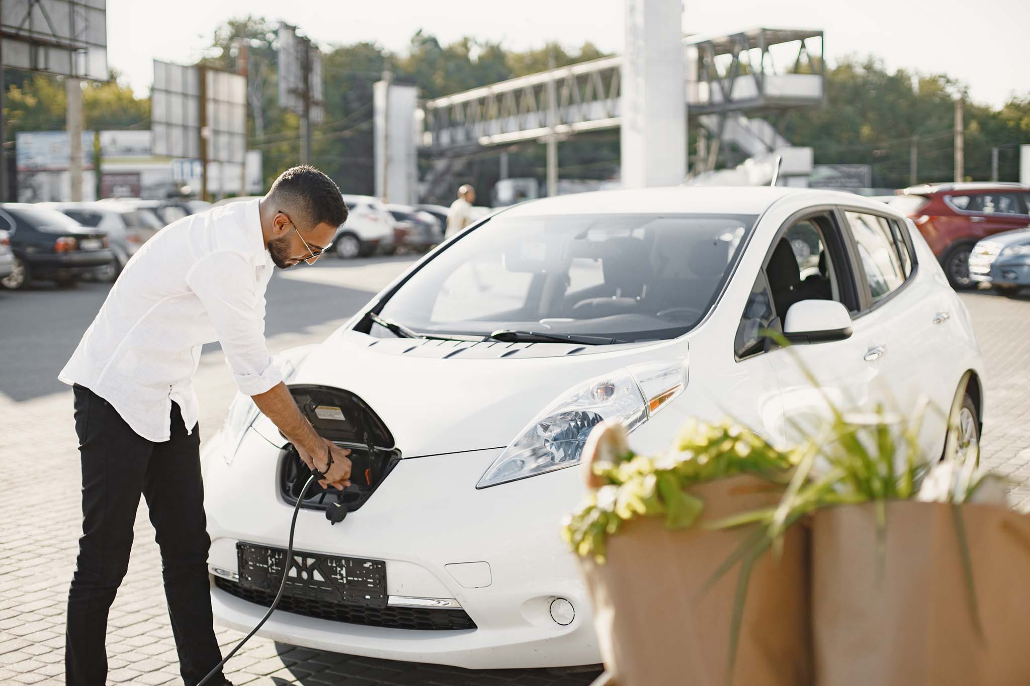 Young adult man charging his electric car in the city. Eco electric car concept.