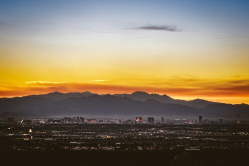 Las Vegas at sunset with the mountains visible behind the city skyline.