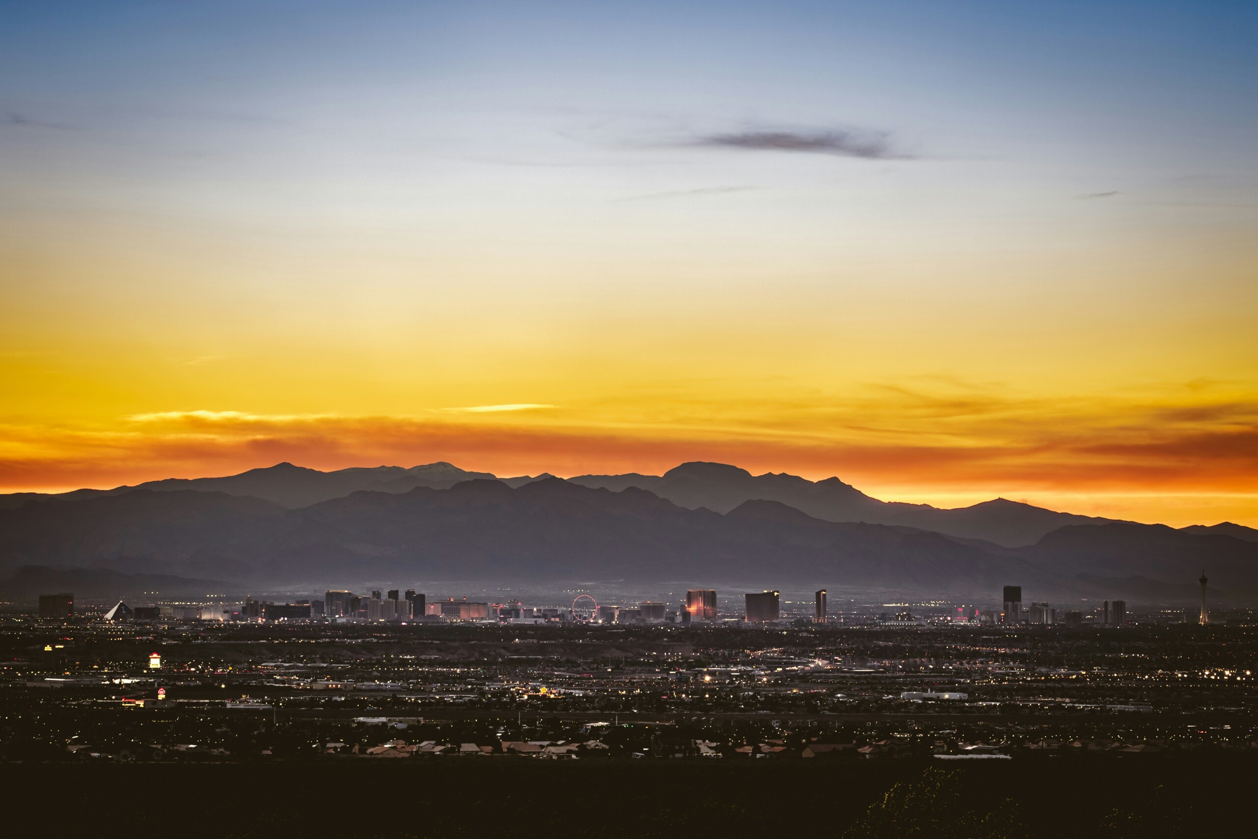 Las Vegas at sunset with the mountains visible behind the city skyline.