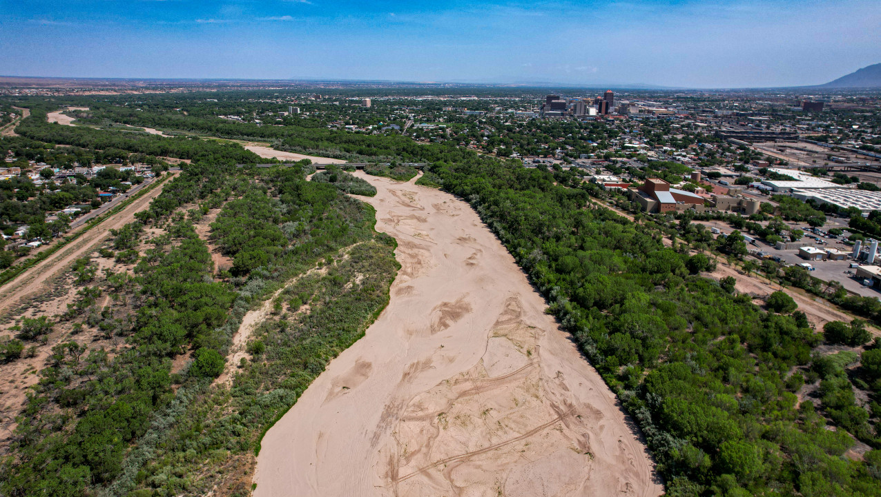 A dry stretch of the Rio Grande with the Albuquerque skyline in the background.